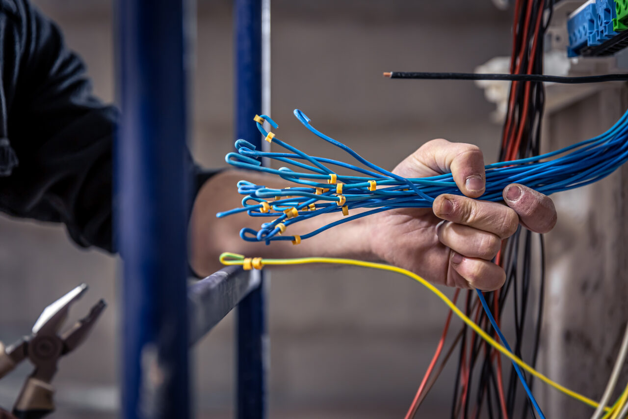 A construction electrician cuts a voltage cable during a repair, close up.